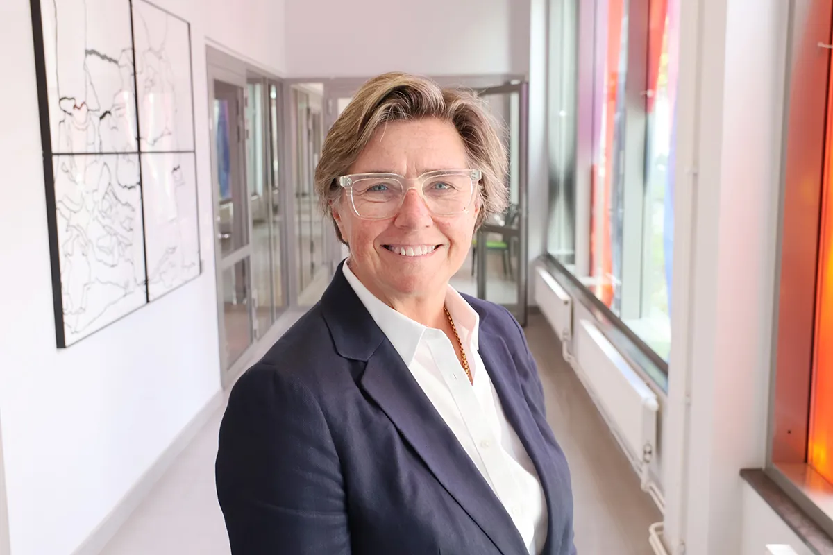 Ulrika Francke i korridor på Stockholms Sjukhem. Hon har glasögon och ler mot kameran.
