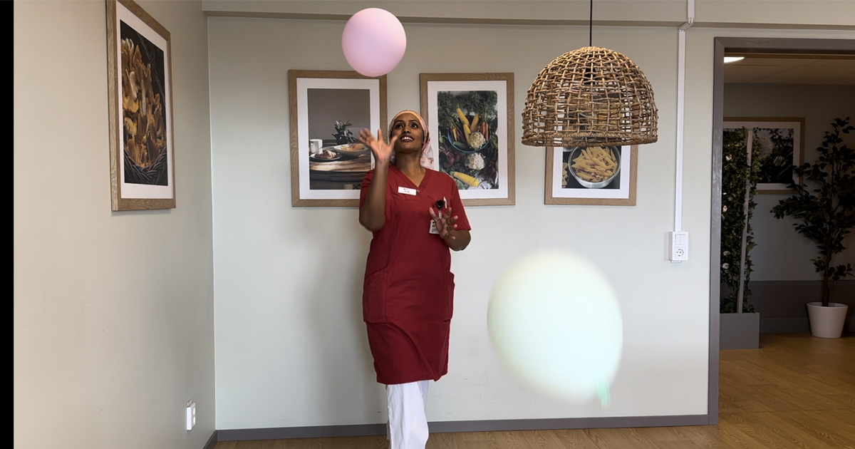 Medarbetare som håller i en aktivitet för de äldre; ballonggympa.