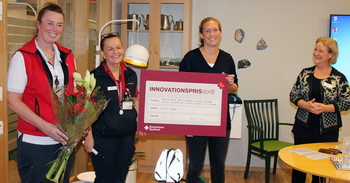 Fyra kvinnor, två i röda västar, håller blommor och prischeck med texten "Innovationspris 2018".