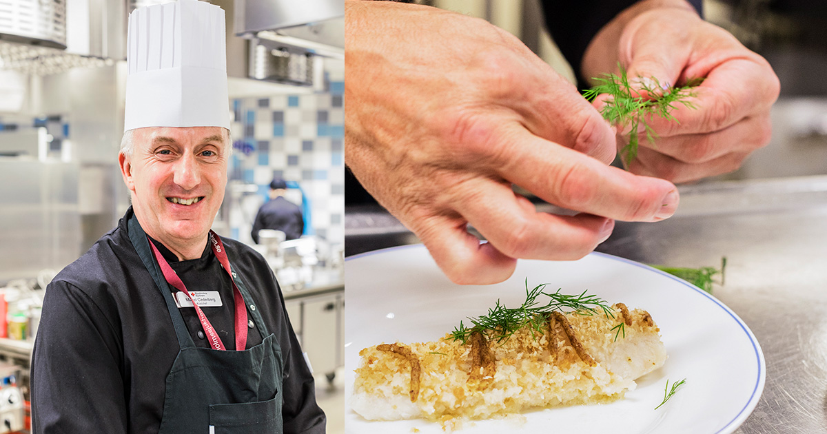 En kock i kök ler, bredvid syns händer som garnerar en tallrik med fisk och dill.