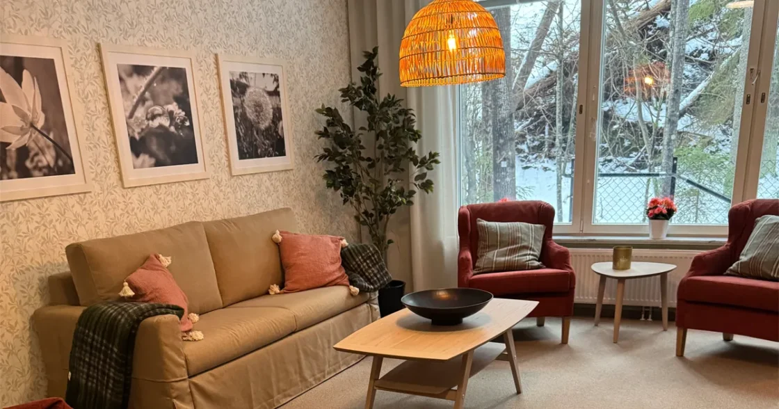 Hemtrevligt inrett vardagsrum på äldreboendet Poesin i Nacka. . Naturen utanför fönstret.