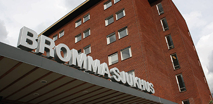 Röd tegelbyggnad med skylten "Bromma sjukhus" ovanför entrén.