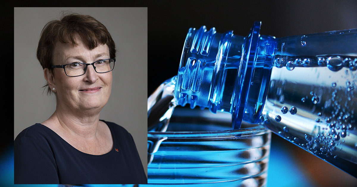 En kvinna med glasögon ler. Bredvid hälls vatten från en blå flaska ner i ett glas.